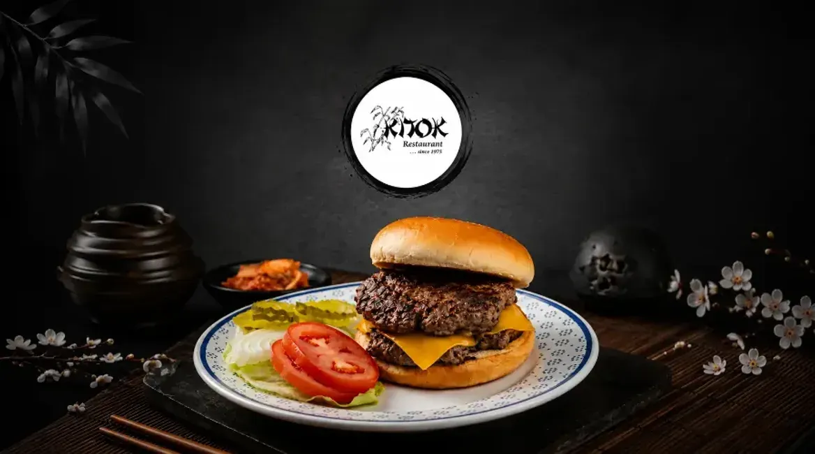 A Kitok cheeseburger with fries on a dark table